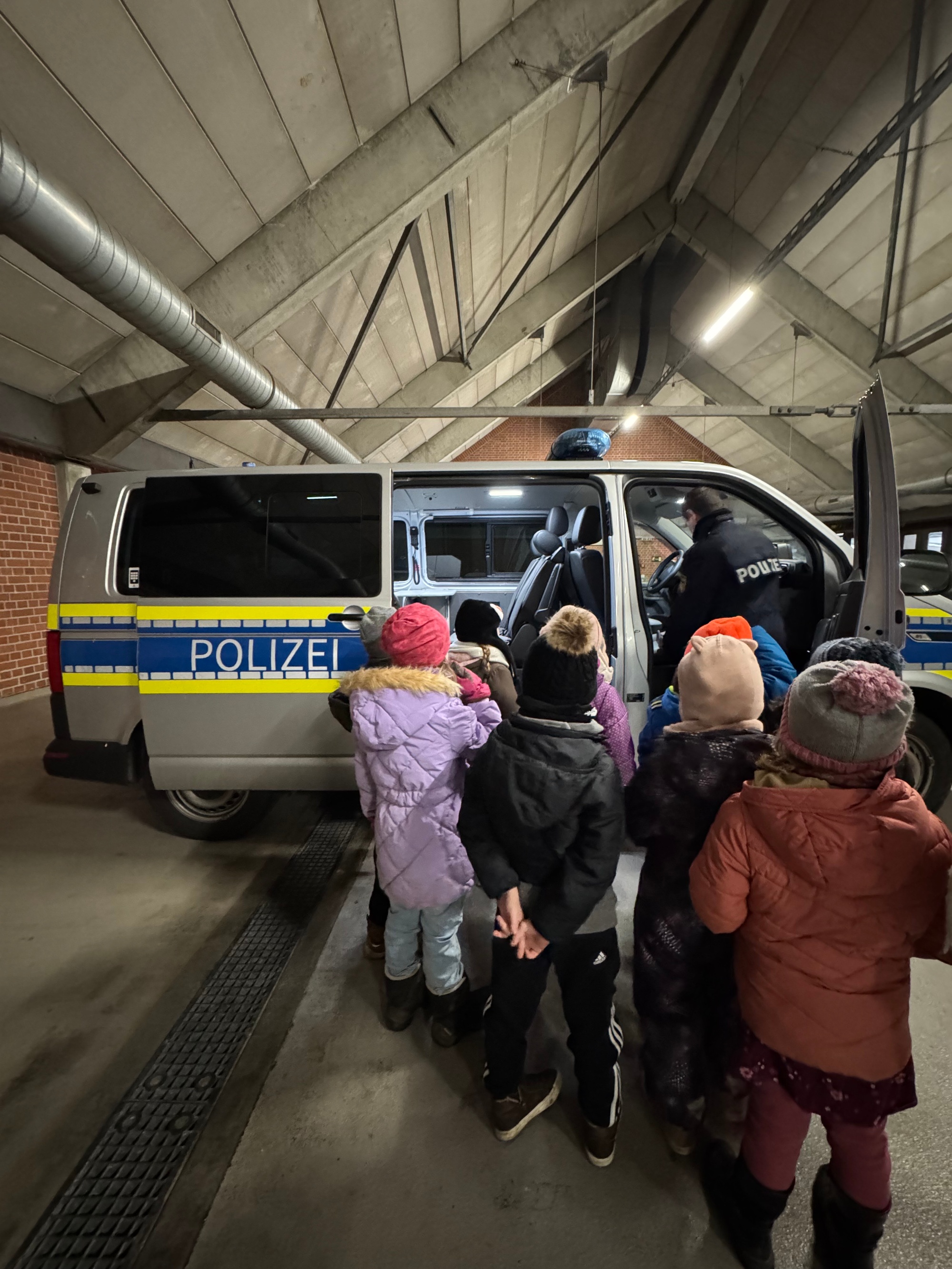 Die Kinder der Kita St. Marien 'farbenfroh' begutachten das Polizeiauto