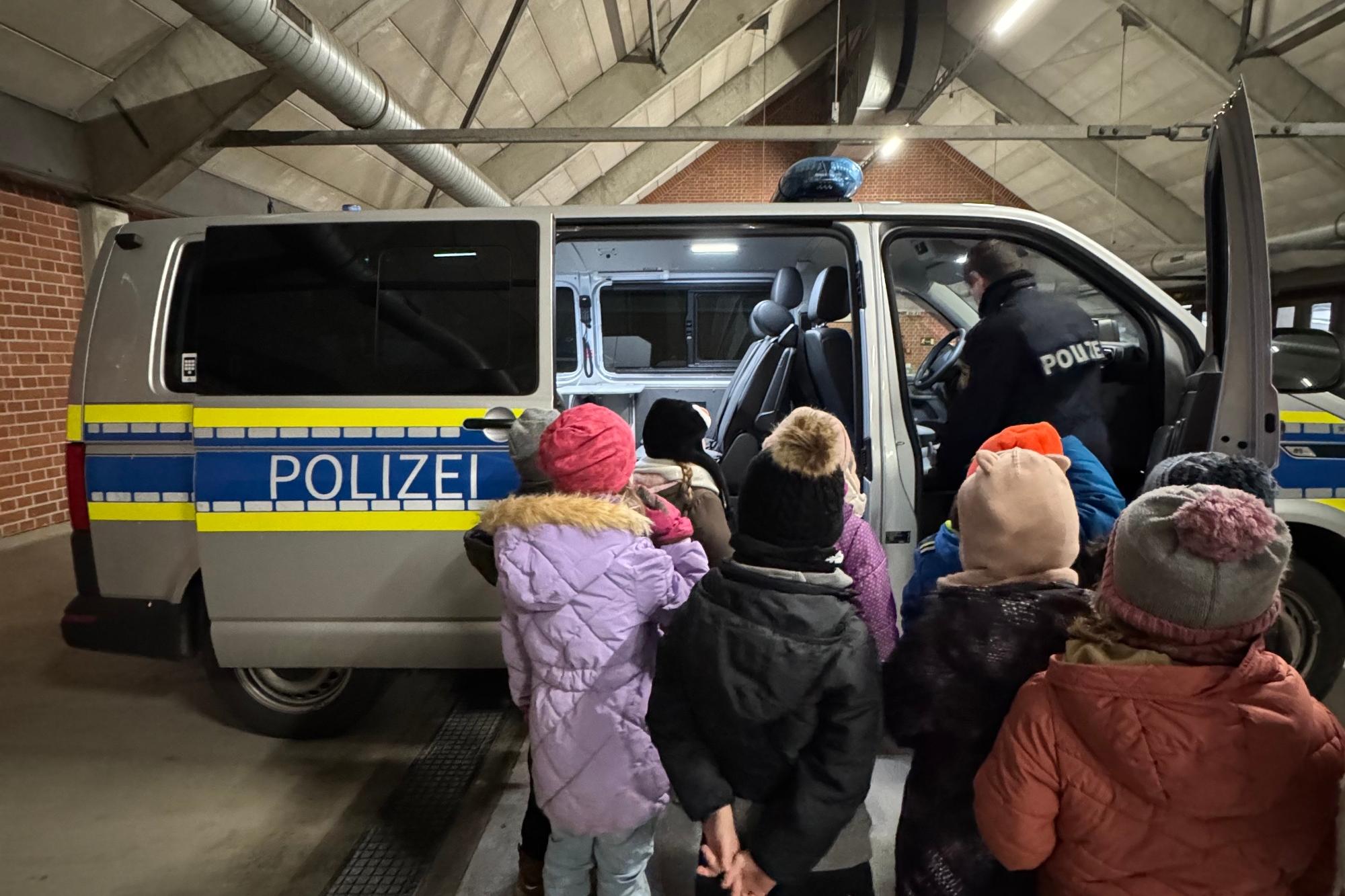 Die Kinder der Kita St. Marien 'farbenfroh' begutachten das Polizeiauto