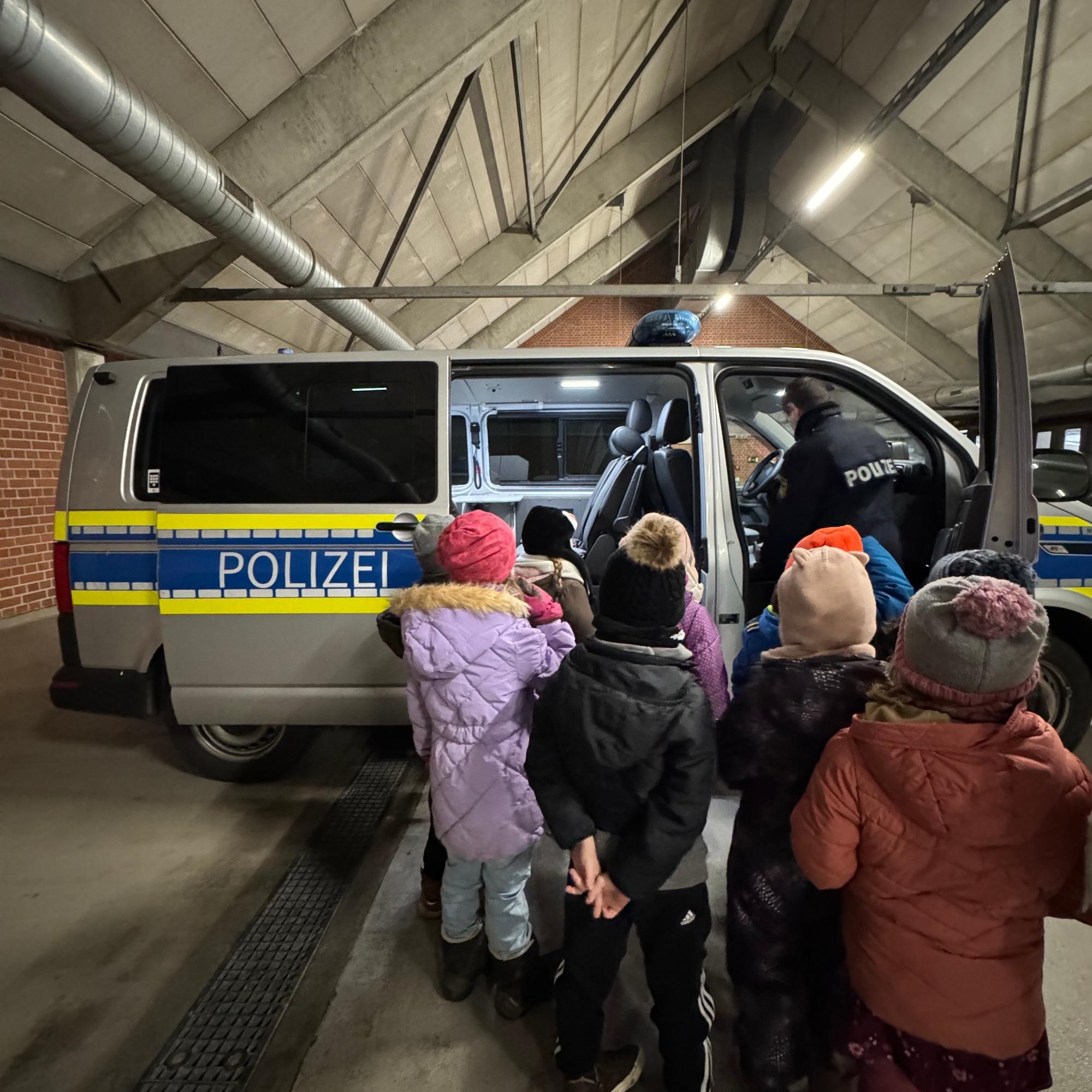 Die Kinder der Kita St. Marien 'farbenfroh' begutachten das Polizeiauto